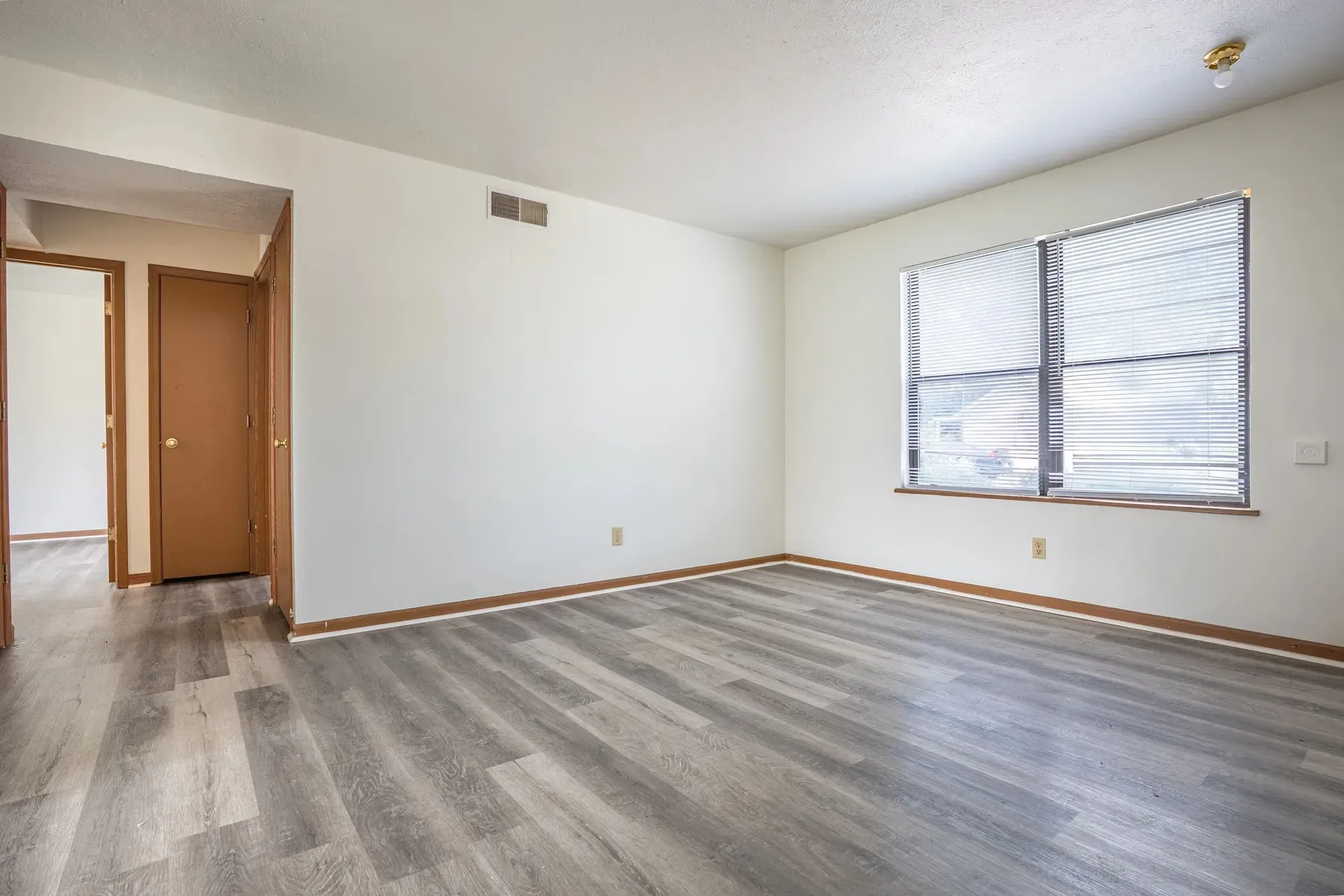 Empty living area with neutral walls and wood-look flooring