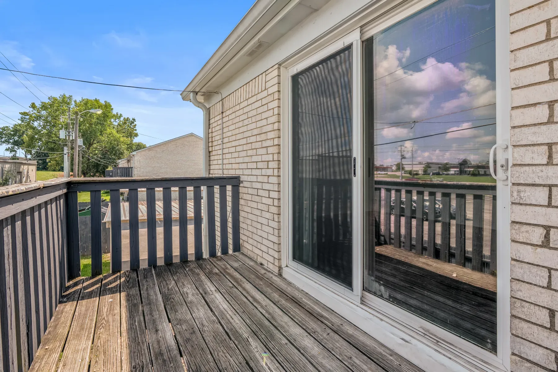 Private wood balcony off a brick apartment building under a blue sky