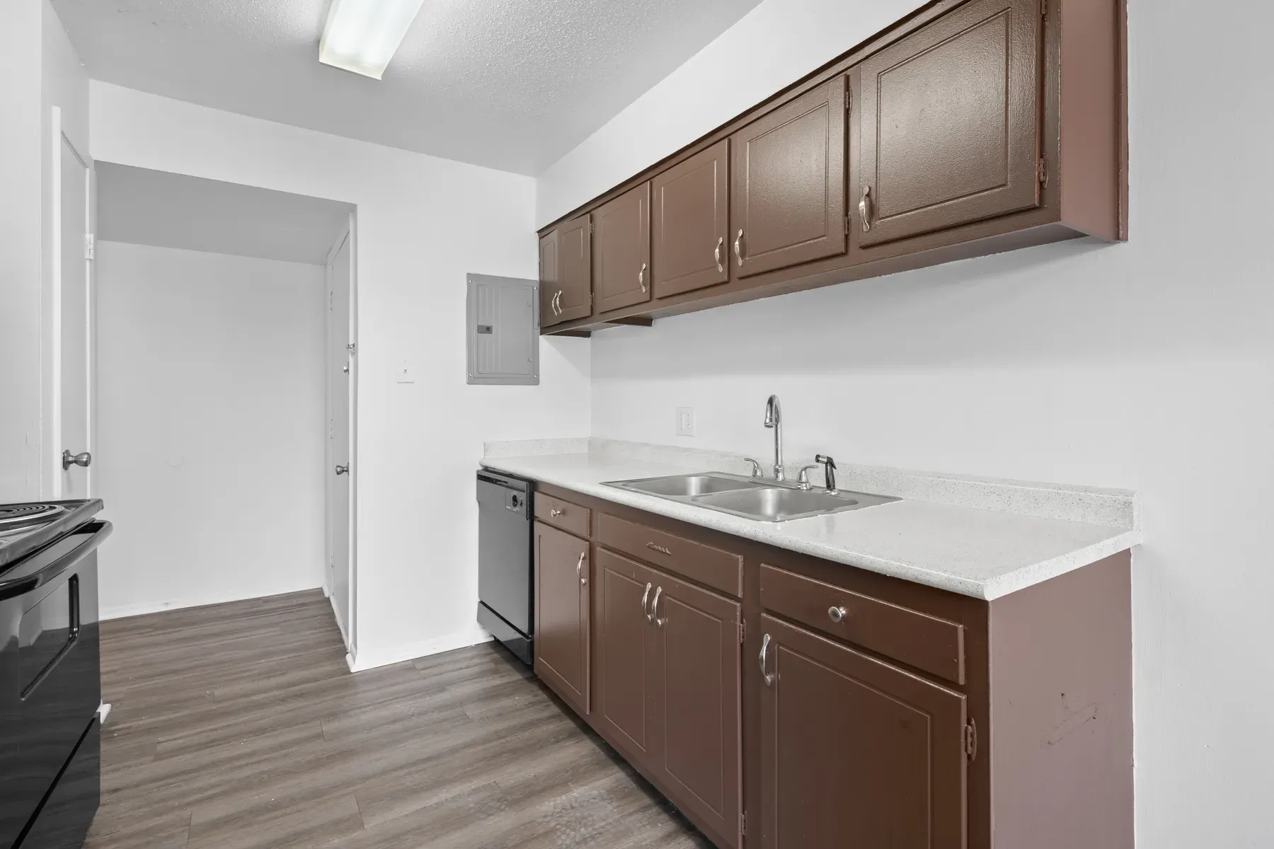 Renovated kitchen with brown cabinets, black appliances and a breakfast bar