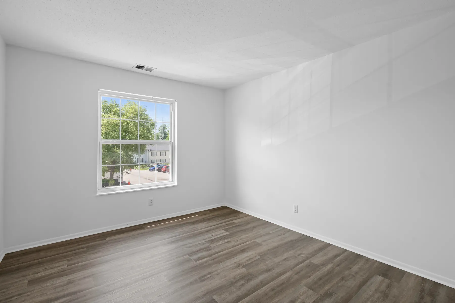 Bright empty living room with wood-look flooring and a large window