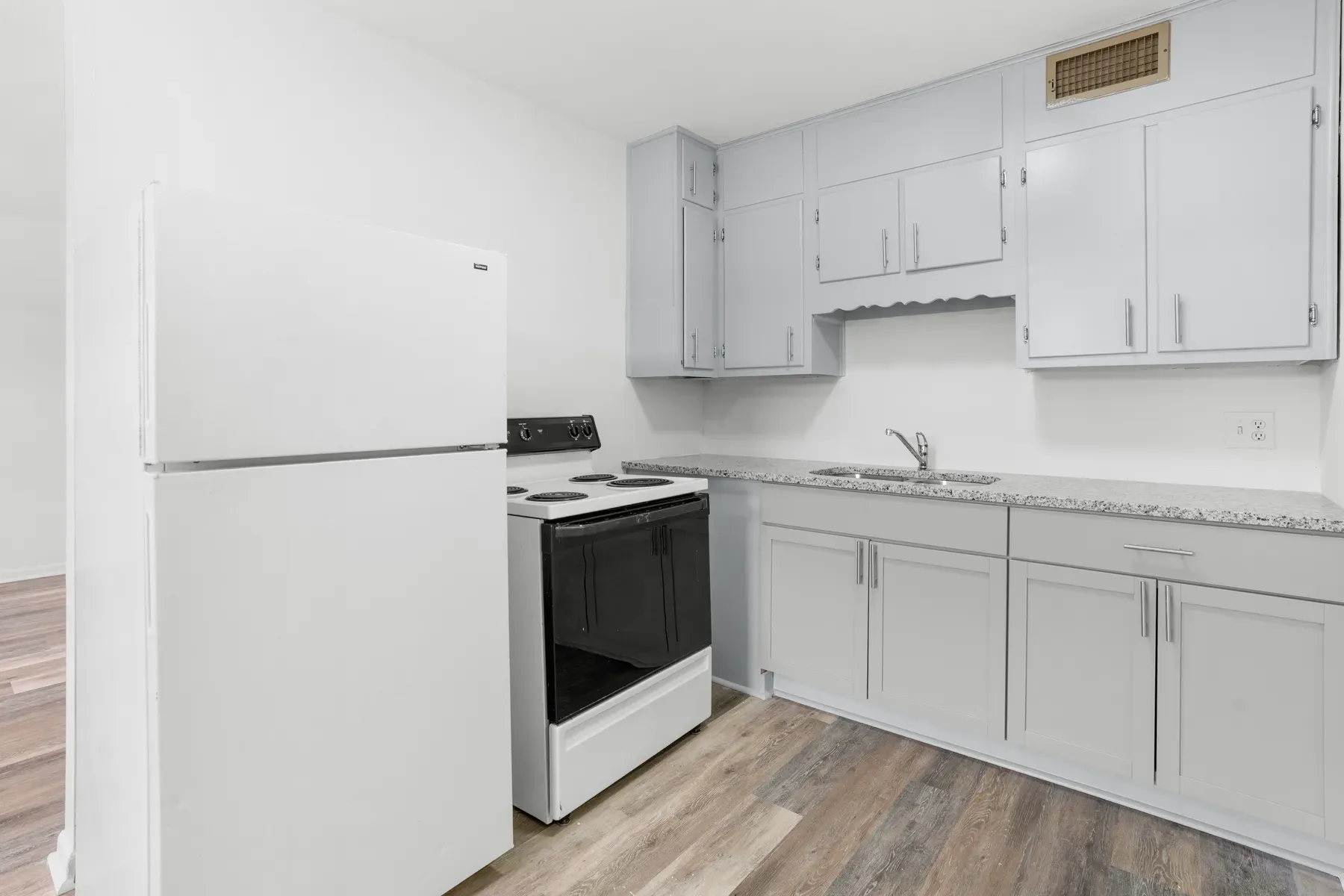 Renovated kitchen with gray cabinets, white appliances and a window
