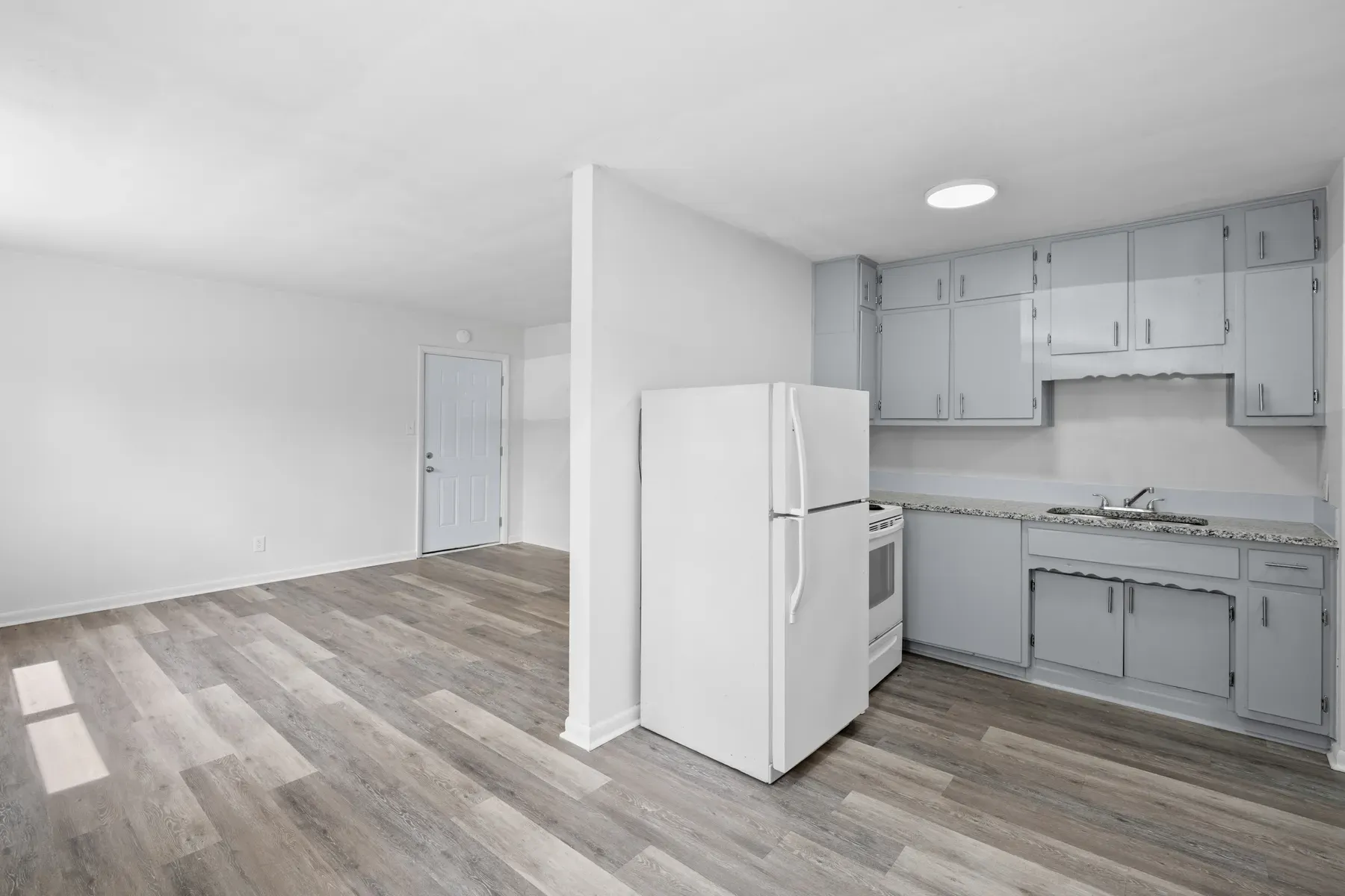 Updated kitchen with white appliances and wood-look flooring