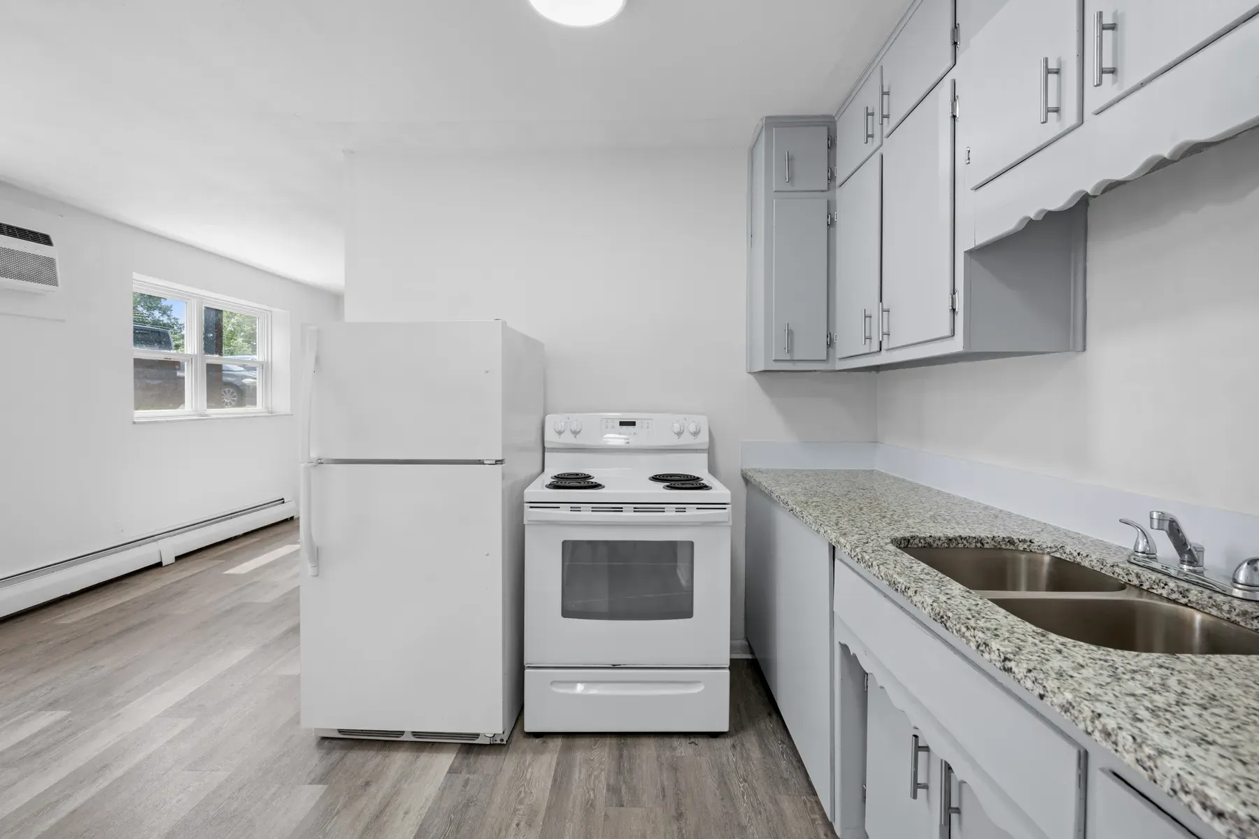 Kitchen with light counters, white appliances and a window
