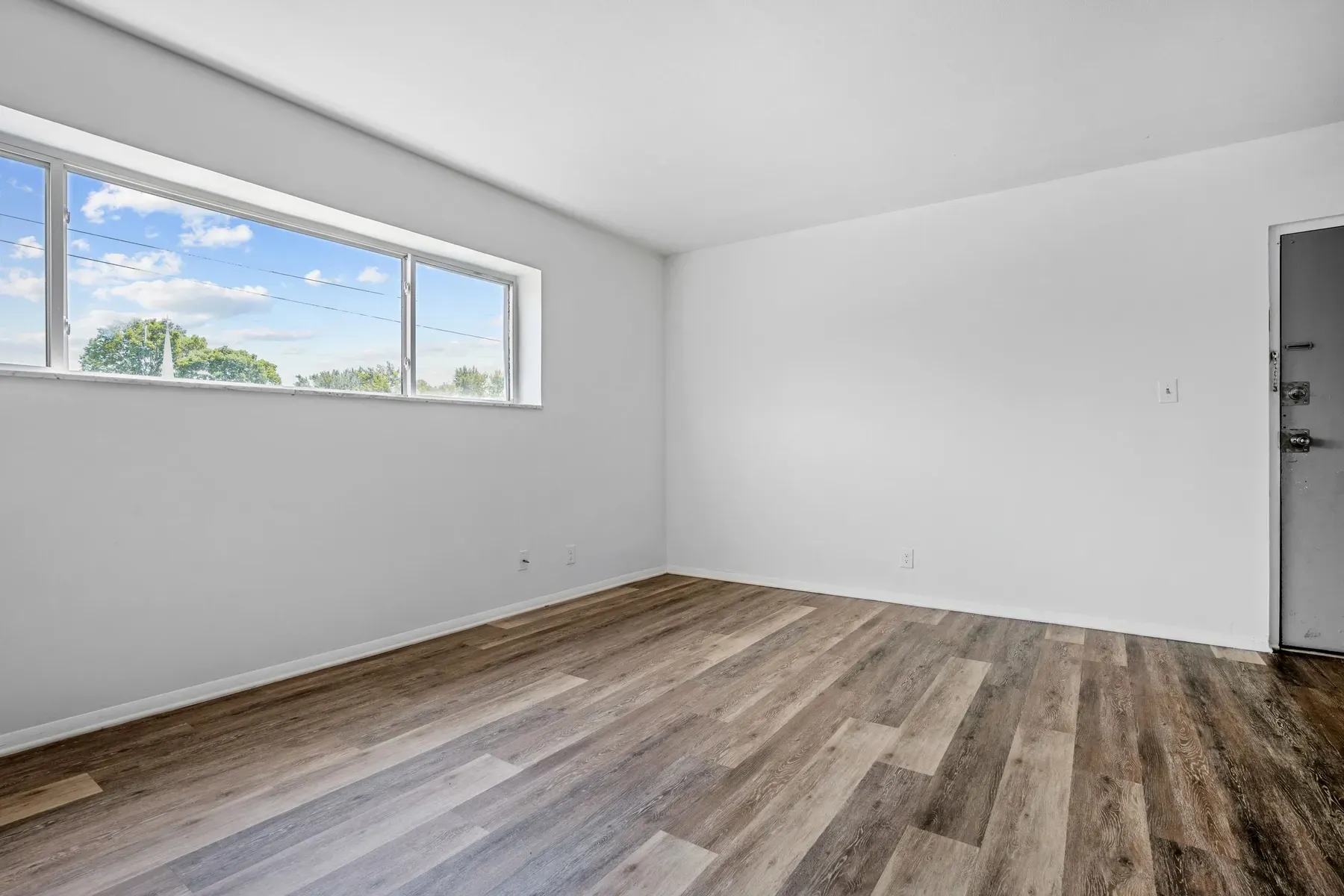 Bright empty living room with wide-plank floors