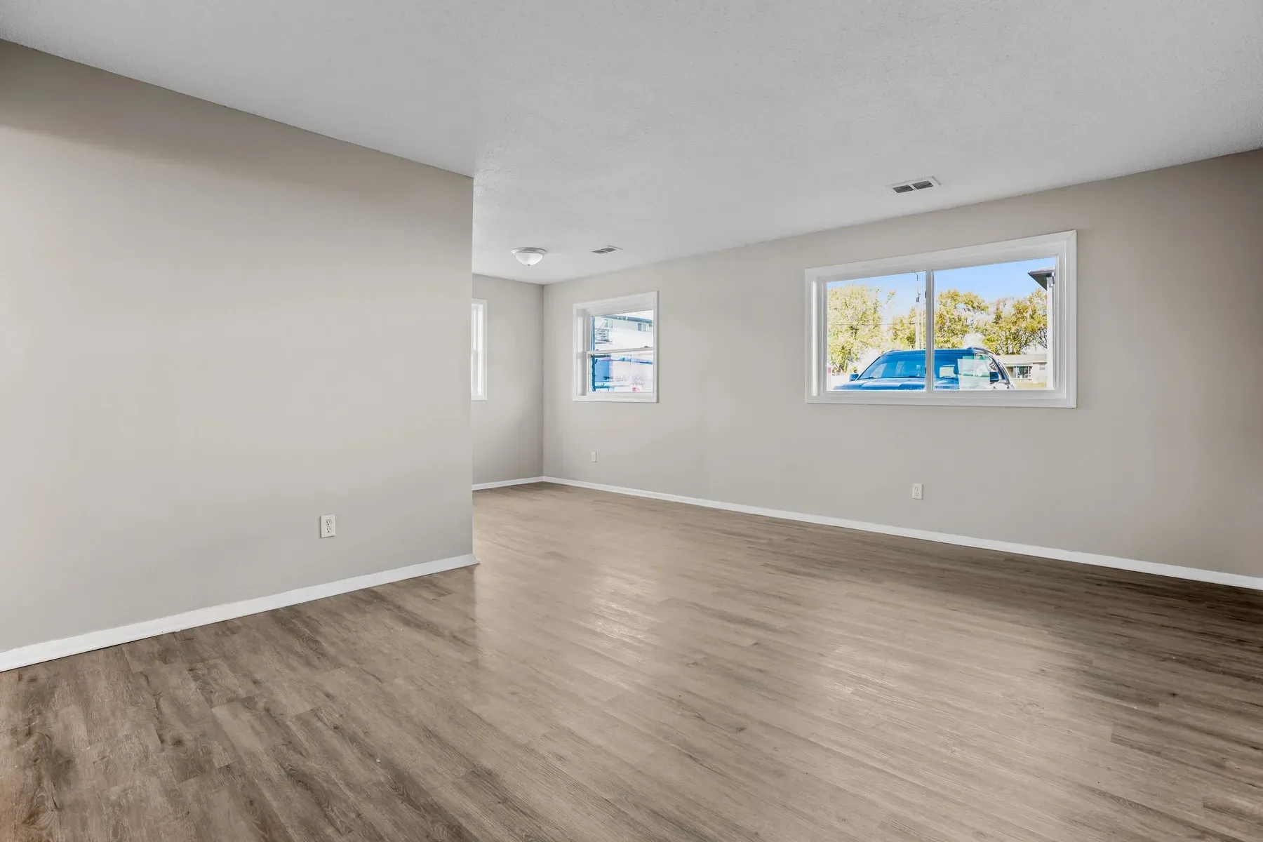 Empty living area with wood-look flooring and a window